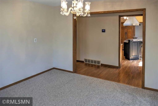 890 Lincoln Ave, Amery, WI 54001 - carpeted spare room with baseboards, a notable chandelier, and visible vents