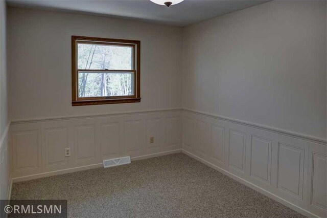 890 Lincoln Ave, Amery, WI 54001 - empty room featuring visible vents, wainscoting, and light colored carpet