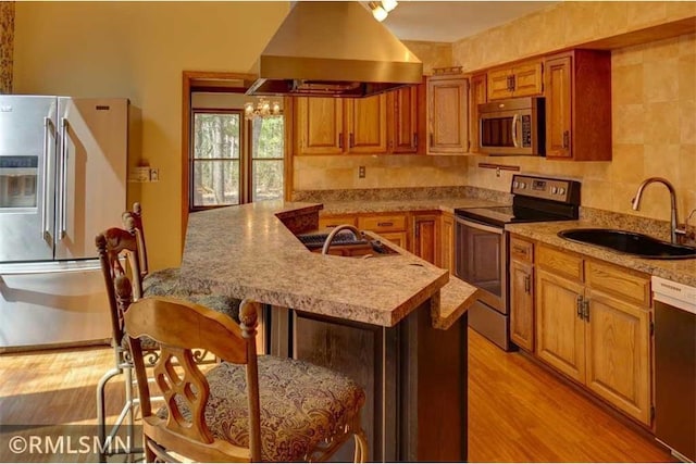 890 Lincoln Ave, Amery, WI 54001 - kitchen featuring brown cabinetry, a kitchen breakfast bar, island exhaust hood, a sink, and appliances with stainless steel finishes