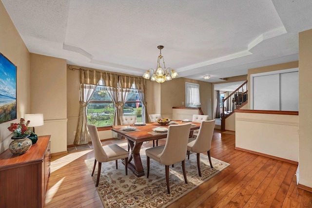 1992 London Rd, Green Bay, WI 54311 - dining space with an inviting chandelier, baseboards, a tray ceiling, and light wood-type flooring