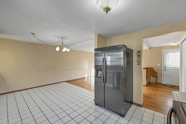 1992 London Rd, Green Bay, WI 54311 - kitchen with stainless steel refrigerator with ice dispenser, baseboards, an inviting chandelier, and light tile patterned floors