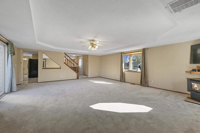 1992 London Rd, Green Bay, WI 54311 - unfurnished living room with carpet flooring, a tray ceiling, visible vents, and stairs