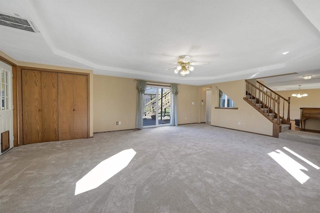 1992 London Rd, Green Bay, WI 54311 - unfurnished living room with visible vents, stairway, a tray ceiling, carpet flooring, and ceiling fan with notable chandelier