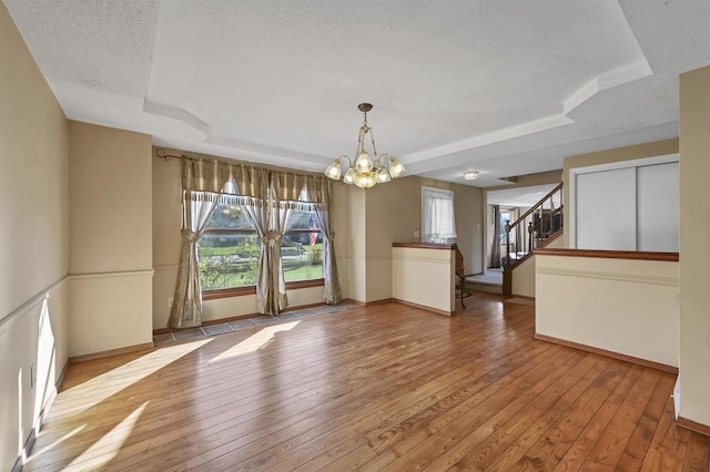 1992 London Rd, Green Bay, WI 54311 - empty room with hardwood / wood-style floors, a tray ceiling, a textured ceiling, and a chandelier