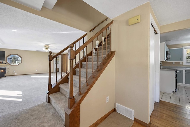1992 London Rd, Green Bay, WI 54311 - staircase featuring a textured ceiling, baseboards, visible vents, and ceiling fan