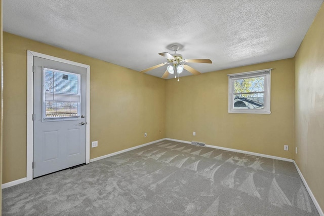 1992 London Rd, Green Bay, WI 54311 - carpeted empty room with a ceiling fan, a textured ceiling, visible vents, and baseboards