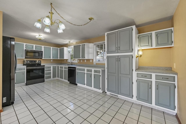 1992 London Rd, Green Bay, WI 54311 - kitchen with black appliances, light countertops, a sink, light tile patterned floors, and a notable chandelier