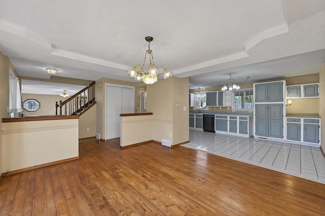 1992 London Rd, Green Bay, WI 54311 - unfurnished living room featuring visible vents, a raised ceiling, baseboards, ceiling fan with notable chandelier, and hardwood / wood-style floors