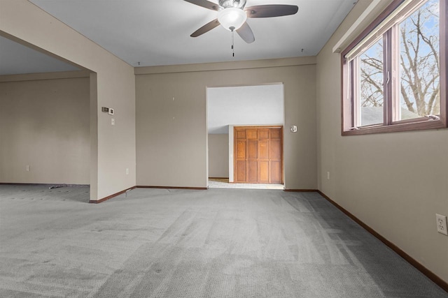 unfurnished room with baseboards, ceiling fan, and carpet