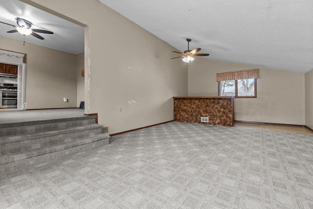 unfurnished living room with carpet flooring, a ceiling fan, stairs, and lofted ceiling