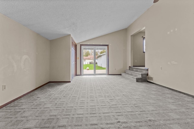 unfurnished living room with a textured ceiling, visible vents, carpet floors, baseboards, and lofted ceiling
