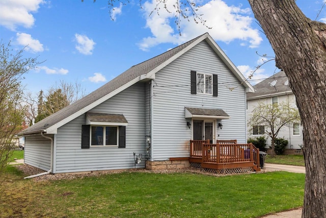 rear view of property featuring a shingled roof, a yard, and a deck