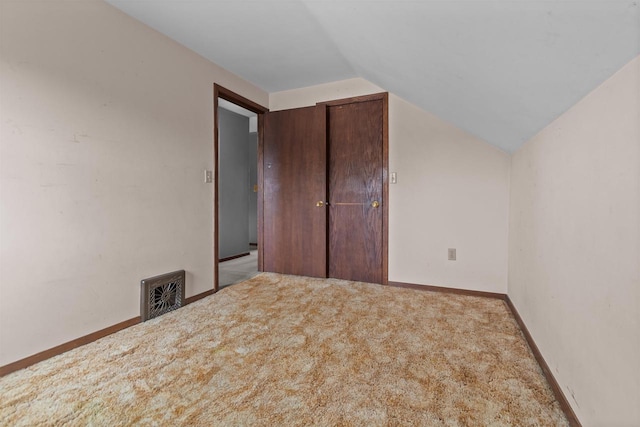 unfurnished bedroom with baseboards, visible vents, carpet, and lofted ceiling