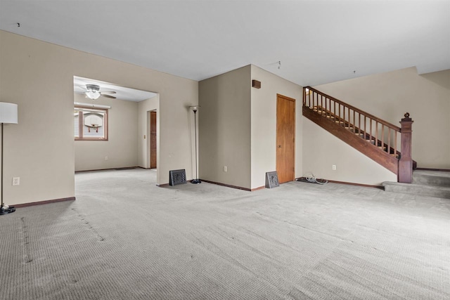 unfurnished living room featuring baseboards, carpet flooring, ceiling fan, and stairway