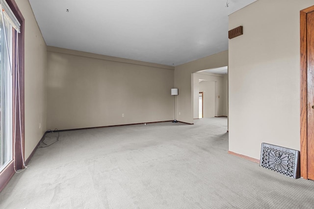spare room featuring light colored carpet and baseboards