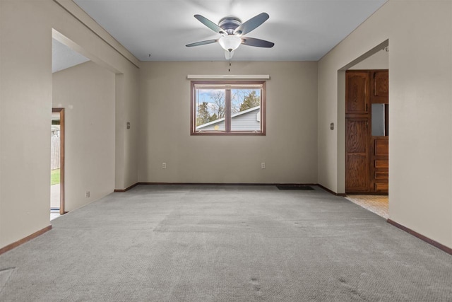 unfurnished room featuring baseboards, a ceiling fan, and carpet