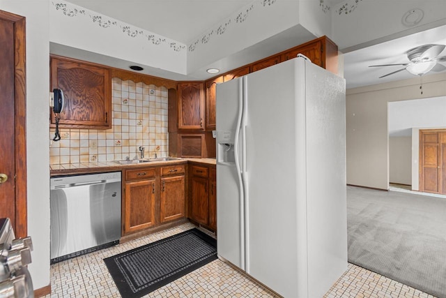 kitchen with a ceiling fan, tile countertops, stainless steel dishwasher, a sink, and white fridge with ice dispenser