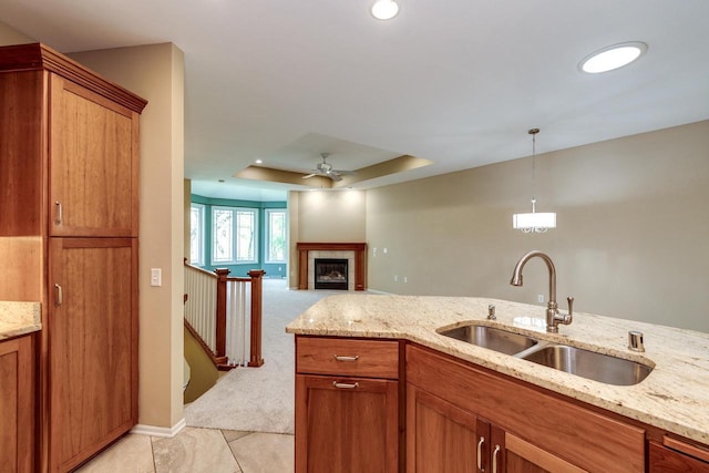 1111 Virgin Lake Dr, Stoughton, WI 53589 - kitchen with a sink, ceiling fan, brown cabinetry, a tray ceiling, and light stone countertops