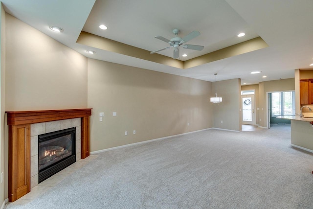 1111 Virgin Lake Dr, Stoughton, WI 53589 - unfurnished living room with recessed lighting, a ceiling fan, light colored carpet, a tile fireplace, and a tray ceiling