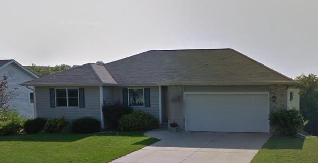 ranch-style house with an attached garage, concrete driveway, and a front lawn