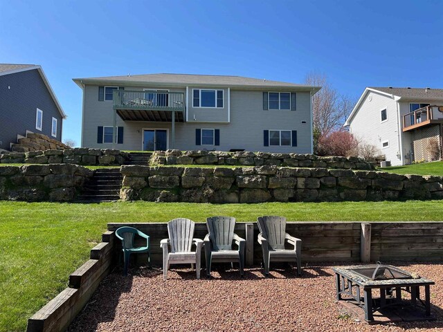 back of property featuring stairs, a fire pit, a yard, and a balcony
