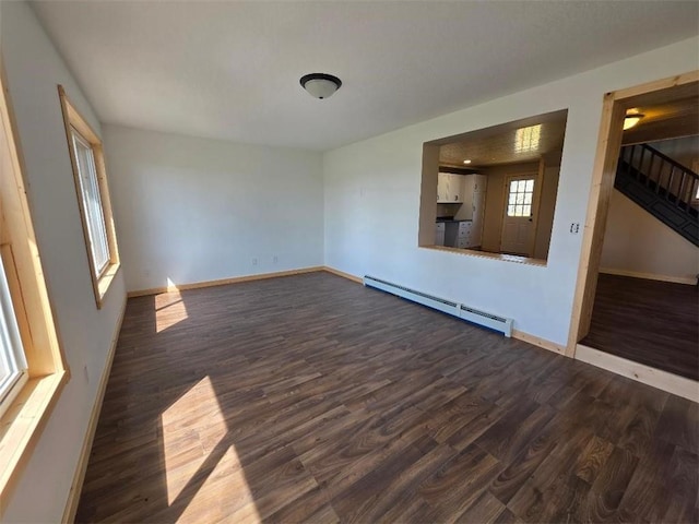 unfurnished room featuring baseboards, a baseboard heating unit, dark wood-style floors, and stairway
