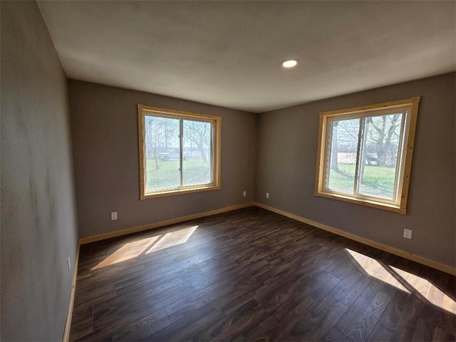 spare room with recessed lighting, baseboards, and dark wood finished floors