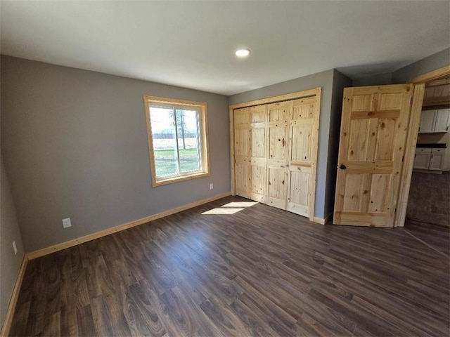 unfurnished bedroom with baseboards, a closet, recessed lighting, and dark wood-type flooring