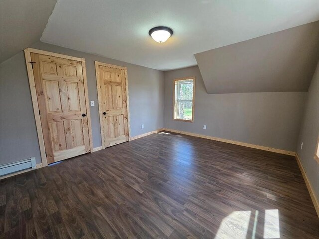 additional living space with baseboards, a baseboard radiator, vaulted ceiling, and dark wood finished floors