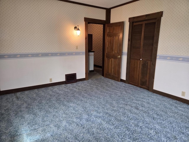 5986 Marsh Rd, Elkhorn, WI 53121 - unfurnished bedroom with visible vents, carpet floors, a closet, ornamental molding, and wallpapered walls