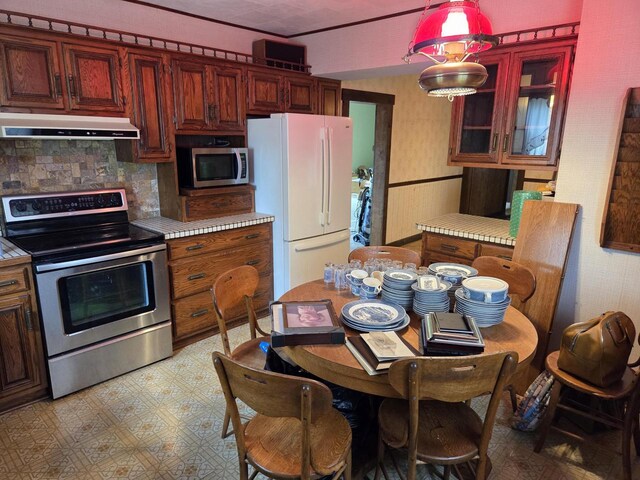 5986 Marsh Rd, Elkhorn, WI 53121 - kitchen with glass insert cabinets, light floors, under cabinet range hood, tasteful backsplash, and stainless steel appliances