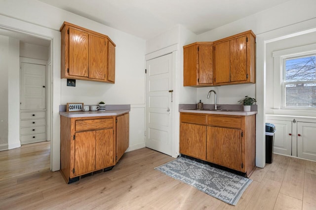 817 E Otjen St, Milwaukee, WI 53207 - kitchen with brown cabinetry, a sink, light wood finished floors, and light countertops