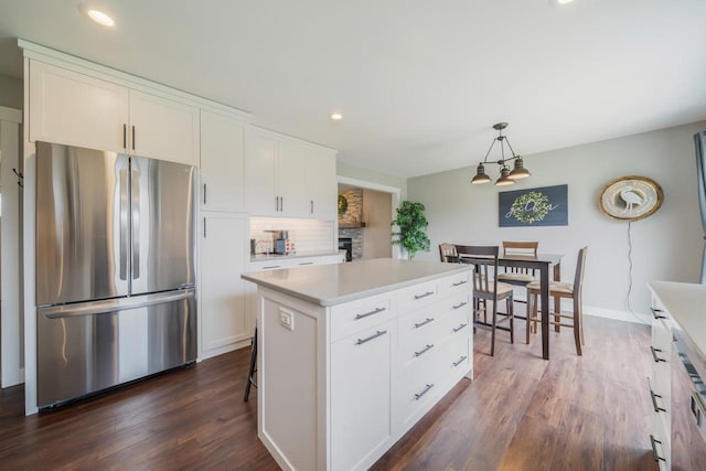 kitchen featuring tasteful backsplash, light countertops, white cabinets, freestanding refrigerator, and dark wood-type flooring