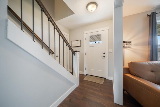 foyer entrance with stairs, dark wood-style flooring, and baseboards