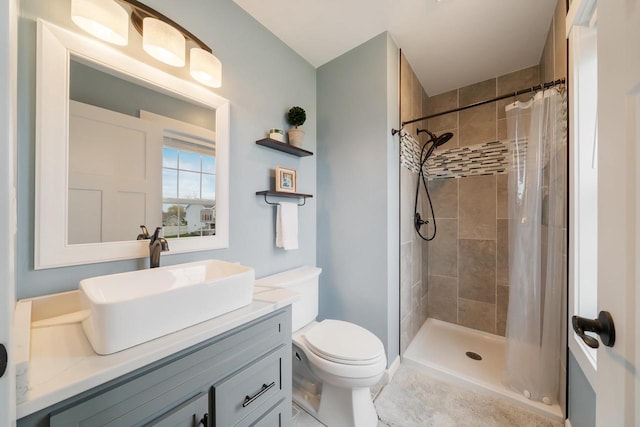 full bath with vanity, a tile shower, and toilet