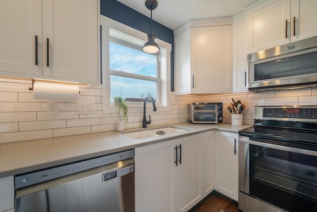 kitchen featuring light countertops, appliances with stainless steel finishes, decorative backsplash, and a sink