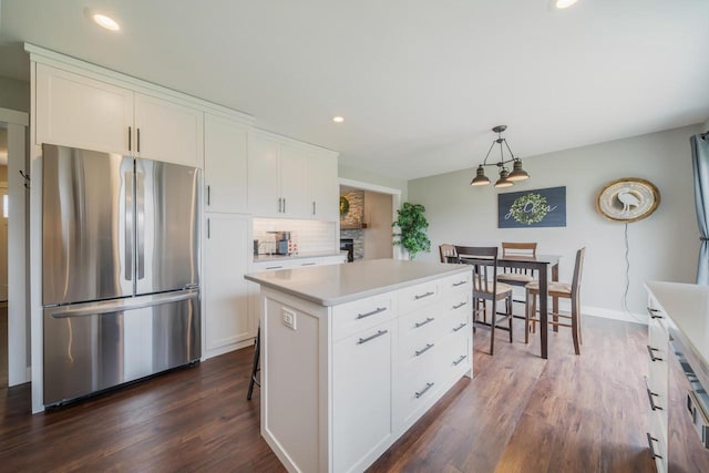 kitchen with freestanding refrigerator, white cabinets, tasteful backsplash, and light countertops