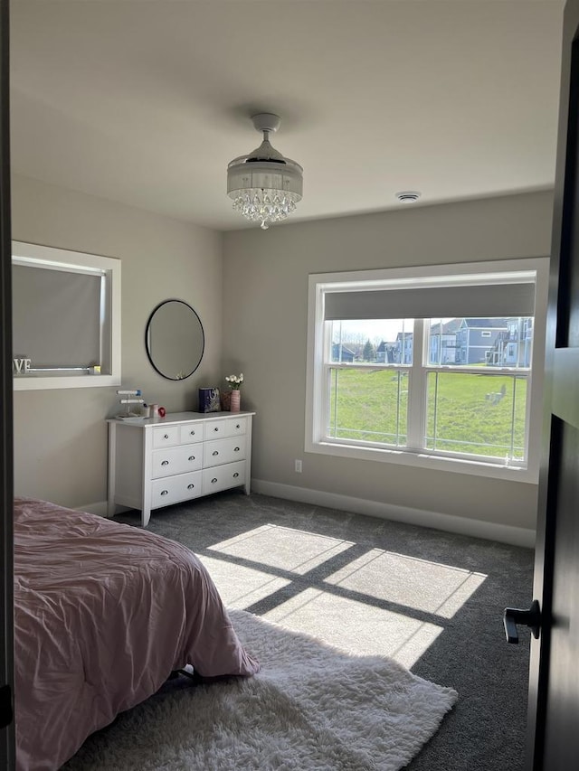 carpeted bedroom with an inviting chandelier and baseboards