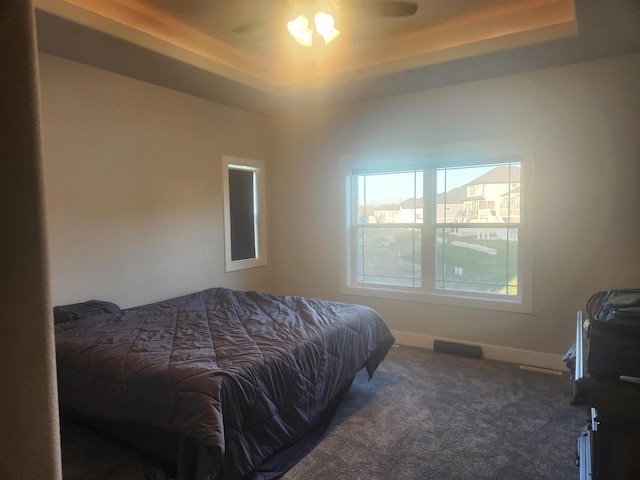carpeted bedroom featuring baseboards and a tray ceiling