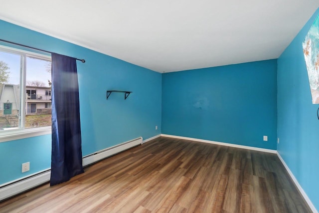 spare room with baseboards, baseboard heating, and wood finished floors