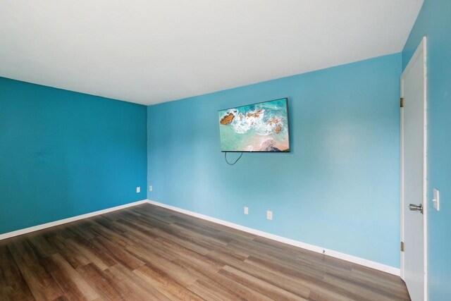 spare room featuring baseboards and wood finished floors