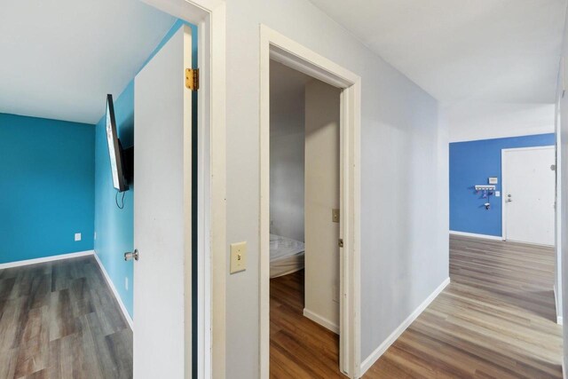 corridor with baseboards and wood finished floors