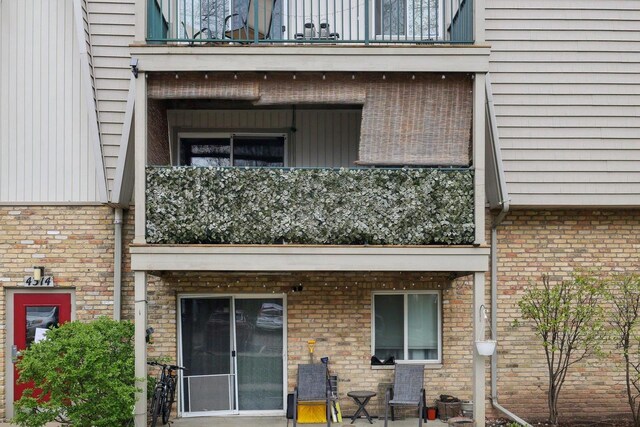 back of property featuring brick siding and a balcony