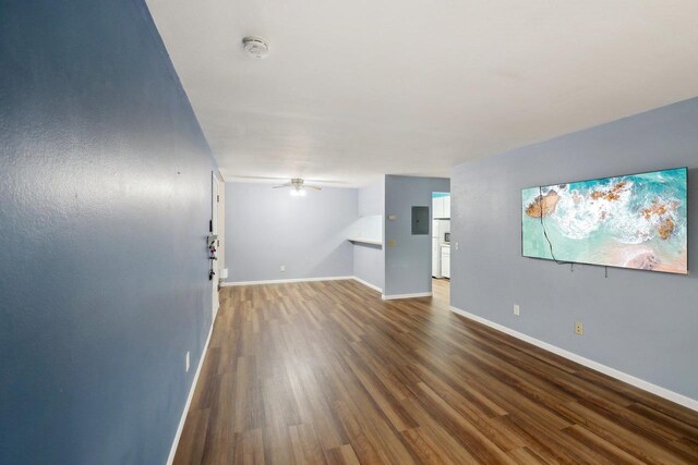 interior space with baseboards, electric panel, a ceiling fan, and wood finished floors