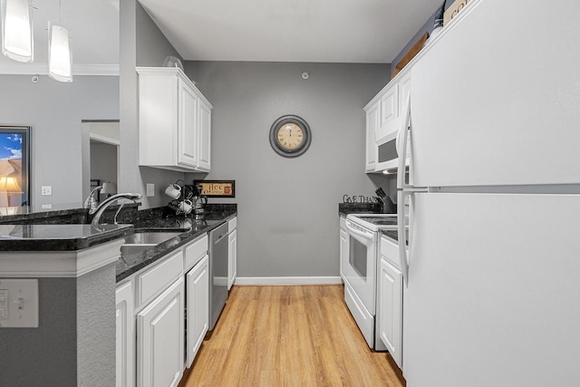 kitchen featuring a sink, white cabinets, light wood finished floors, a peninsula, and white appliances