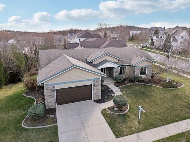 view of front of house with an attached garage, a residential view, and stone siding