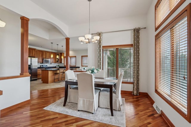 dining space featuring ornate columns, an inviting chandelier, visible vents, and light wood-style floors