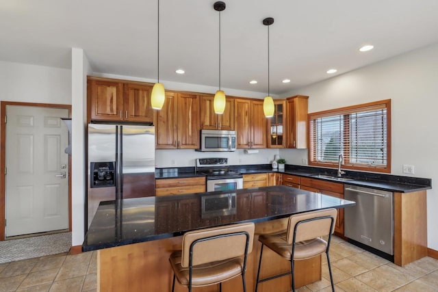 kitchen featuring brown cabinetry, pendant lighting, a center island, a sink, and stainless steel appliances