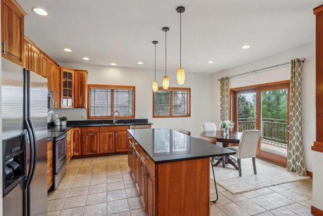 kitchen with brown cabinetry, a breakfast bar area, recessed lighting, a sink, and appliances with stainless steel finishes
