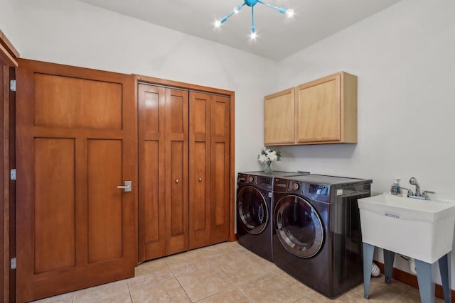 laundry area featuring light tile patterned floors, an inviting chandelier, cabinet space, and washer and clothes dryer